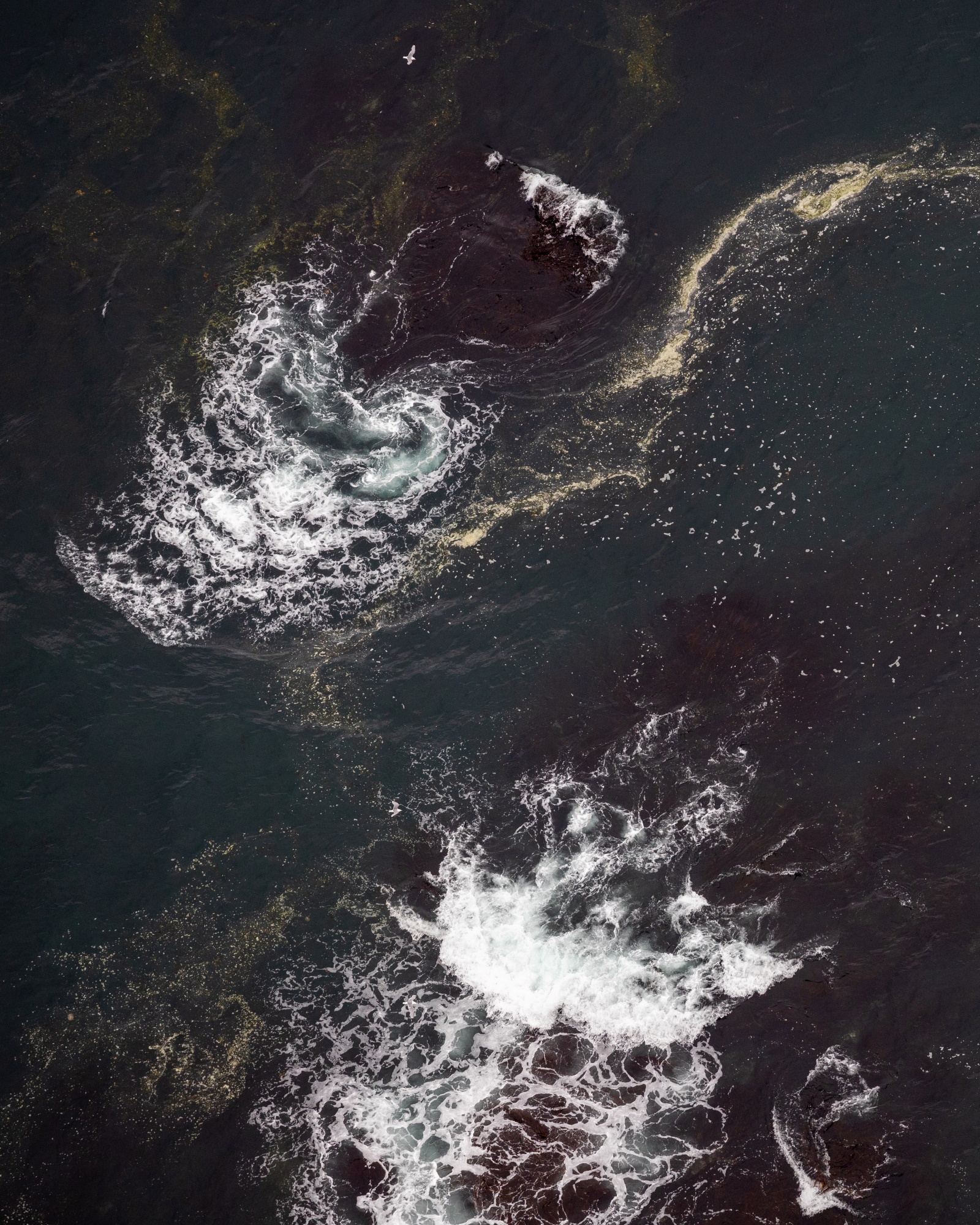 Klettadrangur rísandi úr grænbláu hafinu við Hornstrandir